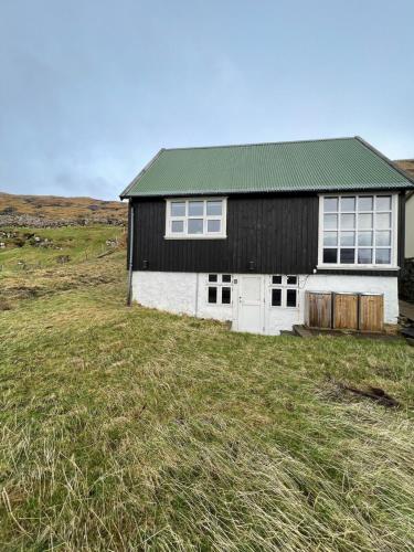 a black and white house on a grassy field at Indulge In Romance & Relaxation At Gillastova in Froðba