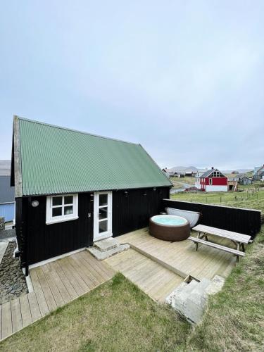 a small black house with a deck and a bench at Indulge In Romance & Relaxation At Gillastova in Froðba