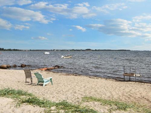 a beach with a chair and a table and water at 6 person holiday home in Sjølund-By Traum in Sjølund