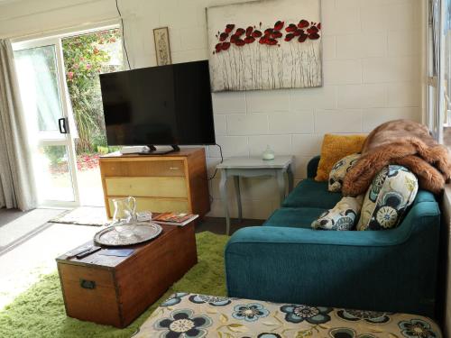 a living room with a blue couch and a tv at Bach on Waikawa 2 bedroom home in Picton
