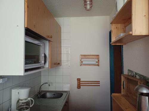 une petite cuisine avec un évier et un micro-ondes dans l'établissement Bonheur des cimes, à Valfréjus