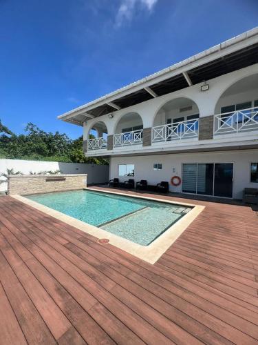 ein Haus mit einem Pool und einer Holzterrasse in der Unterkunft Villa las Orquideas in La Loma