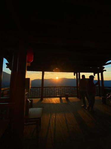 two people walking on the deck of a ship at sunset at Longji Panorama Hotel 龙脊全景楼大酒店 in Longsheng