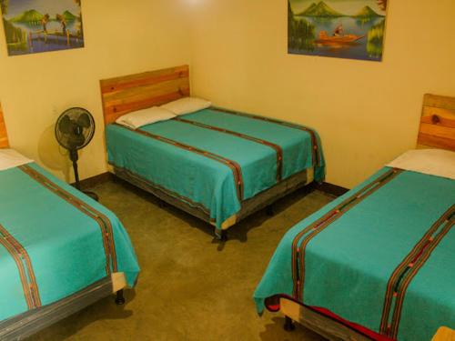 a room with three beds and a fan at Hospedaje Eli Panajachel in Panajachel
