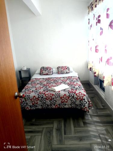 a small bedroom with a bed with a red and black blanket at Alojamiento GAMA in Mexico City