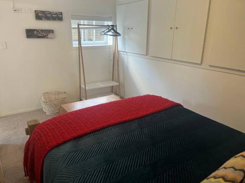 a bedroom with a bed with a red and black blanket at City centre in Hamilton