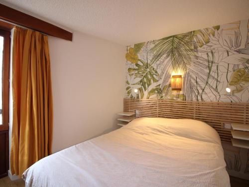 ein Schlafzimmer mit einem weißen Bett und einer tropischen Tapete in der Unterkunft Mont-Dore, T2 avec balcon, parking et wifi proche centre - FR-1-608-271 in Mont-Dore