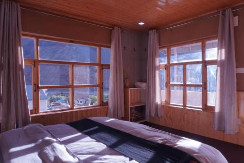 a bedroom with two windows and a bed in it at The Kaza Inn - Your mud house retreat in Kaza