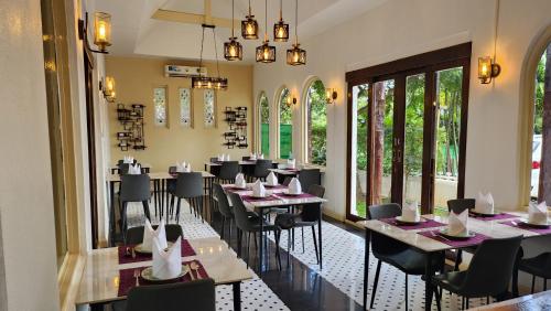 a dining room with tables and chairs and windows at Teewana Resort Chiang Mai in Chiang Mai