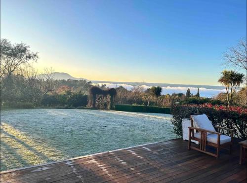 a wooden deck with a bench on top of a yard at Acacia Bay Lodge- Private Manor with Lake and Garden views in Taupo