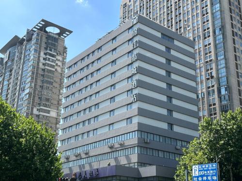 a tall gray building with two tall buildings at Metropolo Hotel Jiangyin Hongqiao Road Baiye Plaza in Jiangyin