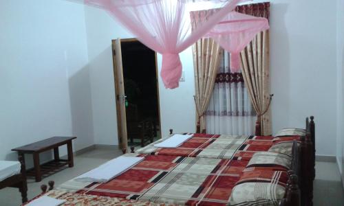a bedroom with a bed and a window with pink curtains at Sea Zone Hotel Nilaveli in Nilaveli