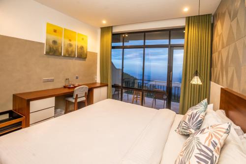 a bedroom with a bed and a desk and a balcony at leisure Mount View in Haputale