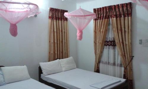 a room with two beds and pink curtains at Sea Zone Hotel Nilaveli in Nilaveli