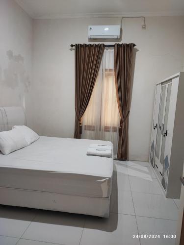 a bedroom with a bed and a window with curtains at Zavira House Purwokerto in Purwokerto