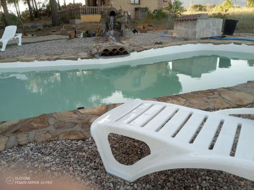 a white bench sitting next to a pool of water at El Pinar del Rondero J&M Con Piscina Natural in Sotillo de la Adrada
