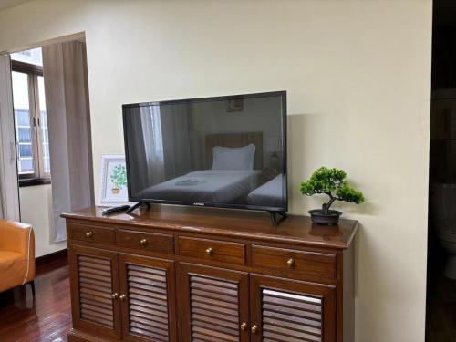 a flat screen tv on a wooden dresser with a bed at Apamet Hotel Sukhumvit 55 in Khlong Toei
