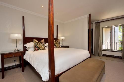 a bedroom with a bed with a four poster bed sidx sidx sidx sidx at The Syrene Boutique Hotel in Johannesburg