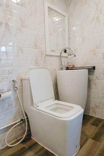 a white toilet in a bathroom with a window at 独立庭院 花园式的两卧两卫民宿 近mrt 2 in Bang O