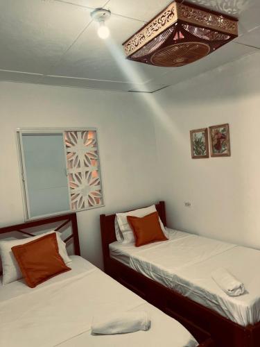 a room with two beds and a ceiling at La Casita De Emma in Ríohacha