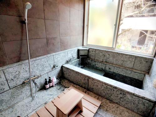 a bathroom with a bath tub with a window at シダーリトリートハウス in Futo