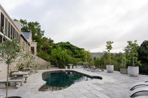 una piscina con bancos y un patio con en Avemore Time Out - full power back up, en Stellenbosch