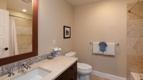 a bathroom with a sink and a toilet and a mirror at SAND CASTLE Modern KaMilo 4BR Home with Ocean Views Bikes in Waikoloa