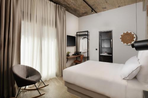 une chambre avec un lit blanc et une chaise dans l'établissement Anise, Aluma Hotels & Resorts, à Athènes