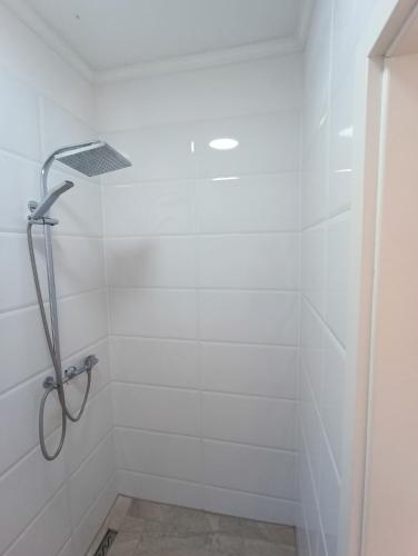 a shower in a bathroom with white tiles at GranseeHOSTEL in Gransee