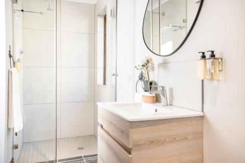 a white bathroom with a sink and a mirror at Avemore Orchard Apartment - with full Backup power in Stellenbosch