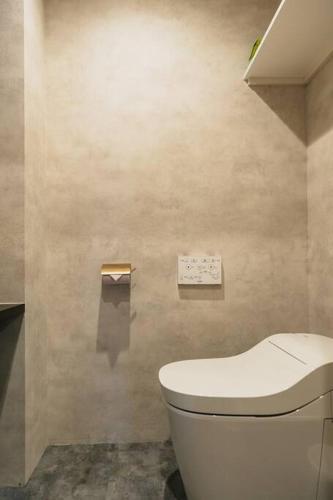 a bathroom with a white toilet in a room at 那覇 国際通りまで30秒 1日1組限定のモダン貸切ステイ in Naha