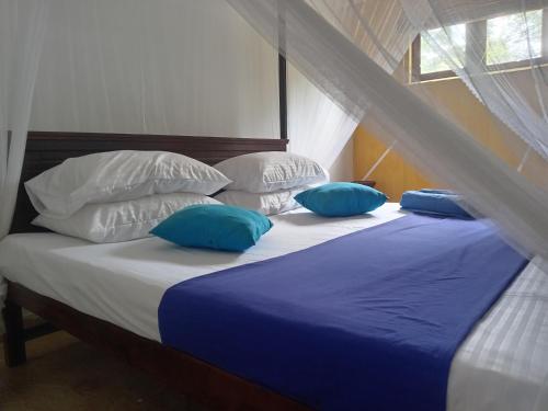 a bed with blue and white pillows on it at freedom house in Unawatuna