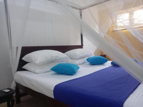 a bedroom with a bed with blue pillows at freedom house in Unawatuna