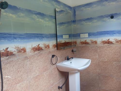 a bathroom with a sink and a mural of the beach at freedom house in Unawatuna