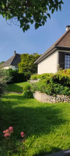 une maison avec une cour ornée d'herbe verte et de fleurs dans l'établissement Bed and breakfast, à Mantes-la-Ville