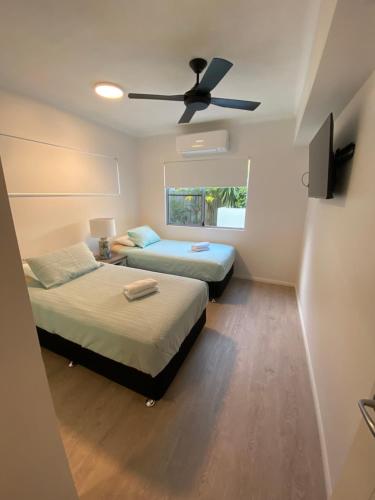 two beds in a room with a ceiling fan at Strand to Stadium - Perfect central location in Townsville City in Townsville