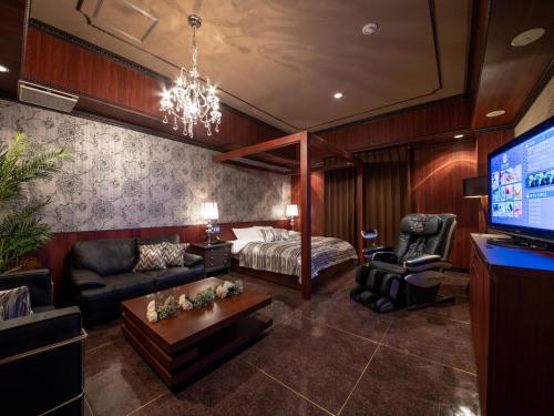 a living room with a bed and a tv at アルバニア in Matsuyama