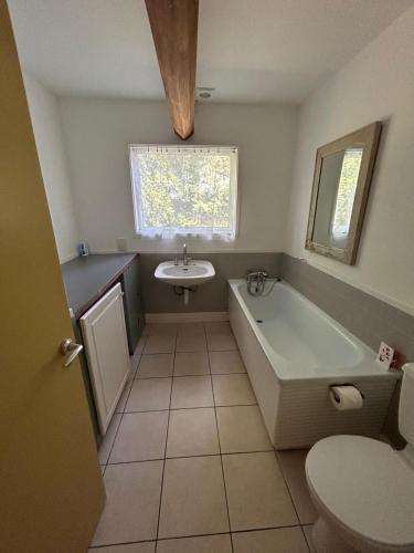 a bathroom with a tub and a sink and a toilet at Wood Place in Diss