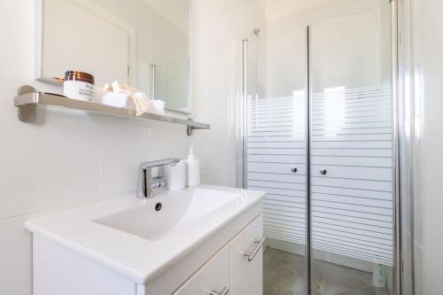 a white bathroom with a sink and a shower at Luxury 4 Bedroom With Amazing View In Ramat Sharet Bayt Vegan in Jerusalem