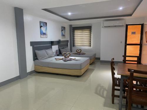 a bedroom with two beds and a table and a table at Dante's Hideaway Guest House in Boracay