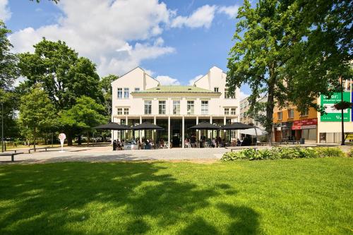 a large white building with black umbrellas in a park at Rezidence Sadová Zlín in Zlín