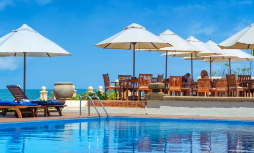 a swimming pool with umbrellas and tables and chairs at Galle Face Hotel in Colombo