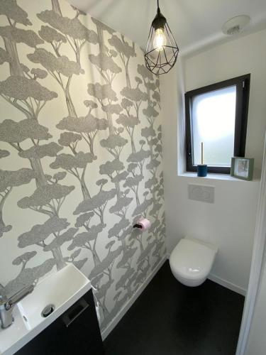 a bathroom with a toilet and a wall with a tree mural at Sittelles lodges cube in Concarneau