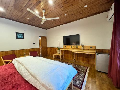 a bedroom with a bed and a flat screen tv at The Pecan Resort in Gilgit