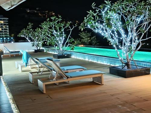 a resort pool with lounge chairs and trees at night at Ratana Platinum Resort Kamala in Kamala Beach