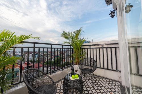 a balcony with two chairs and a table with fruit on it at Madelise Grand Hotel in Hanoi