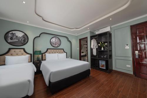 two beds in a room with green walls and wooden floors at Madelise Grand Hotel in Hanoi