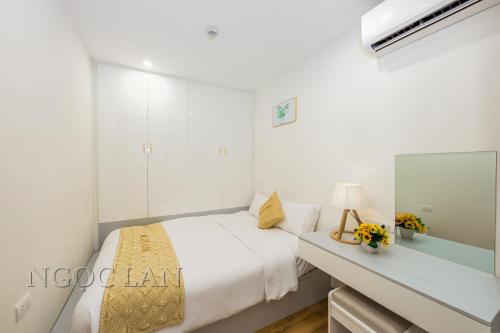 a white bedroom with a bed and a mirror at TMS Quy Nhon - Ngoc Lan Apartments in Quy Nhon