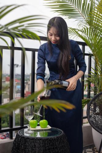 a woman pouring a glass of wine on a table at Madelise Grand Hotel in Hanoi