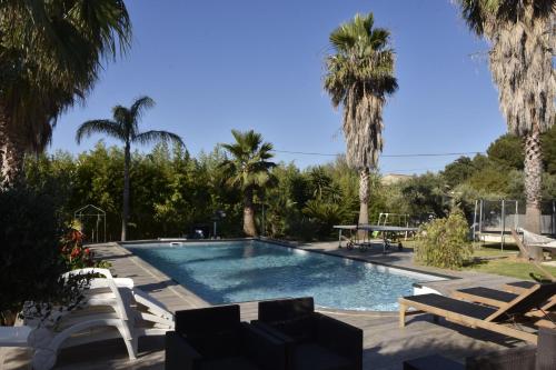 - une piscine bordée de chaises et de palmiers dans l'établissement Bas de Villa tropicale SANARY, à Sanary-sur-Mer